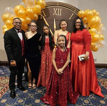 Family of six standing in front of the Gift of Time clock